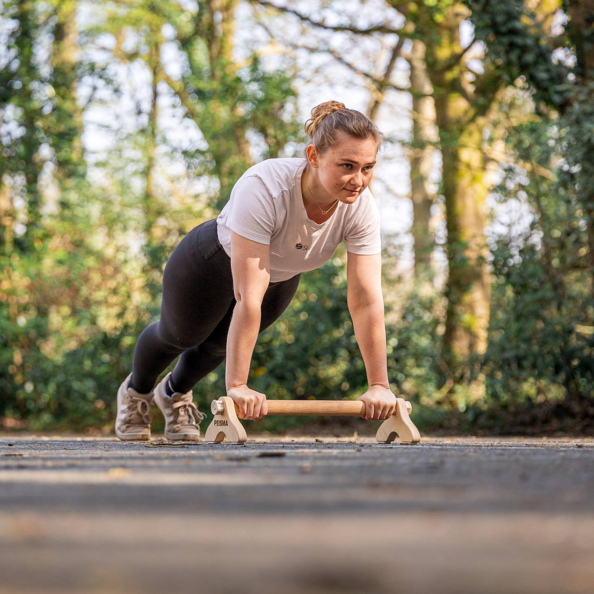 photo d'une femme faisant des pompes sur une seule parallette Peisma sur un terrain de basket