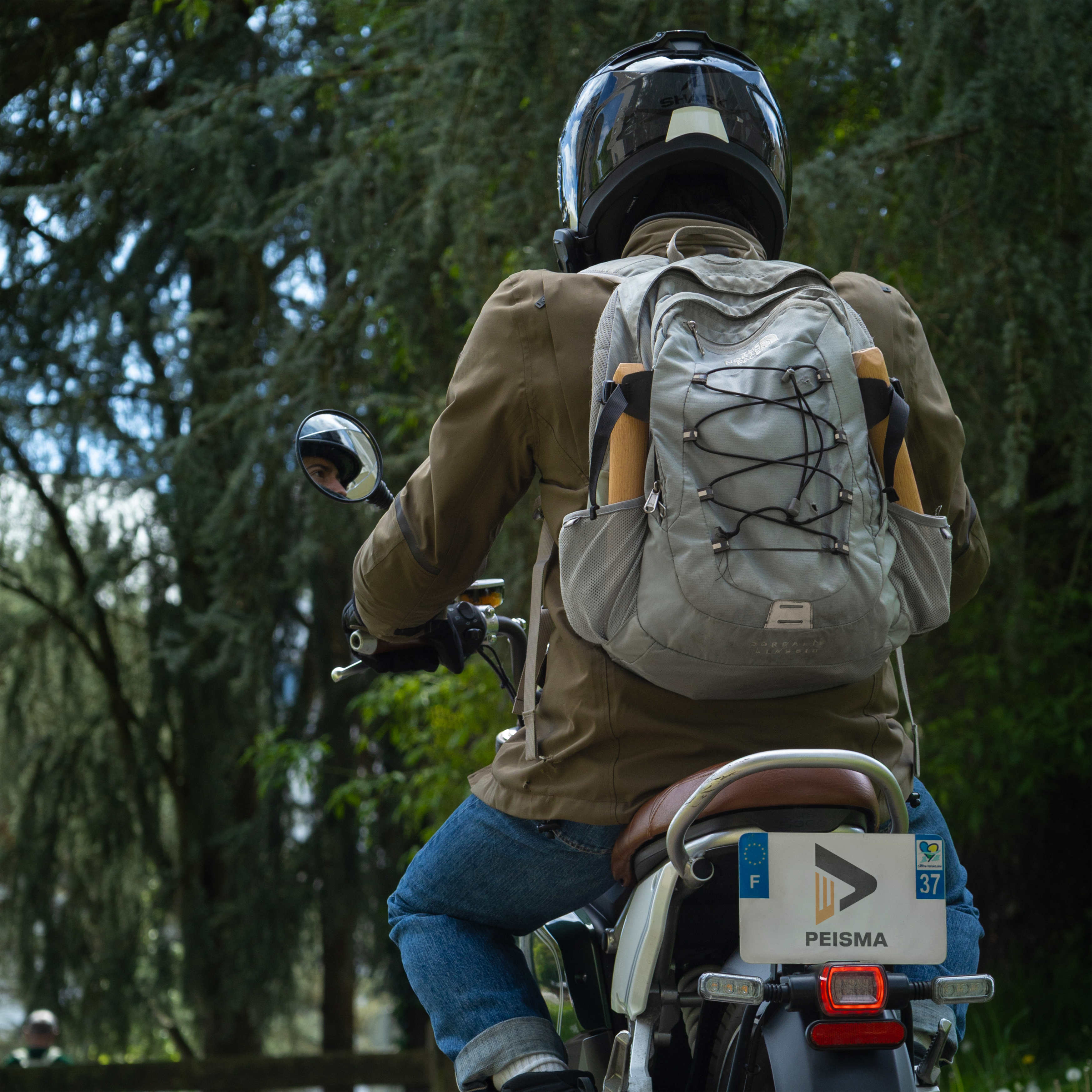 photo d'un motard avec un sac à dos dans lequel on aperçoit les barres des parallettes Peisma sur les côtés