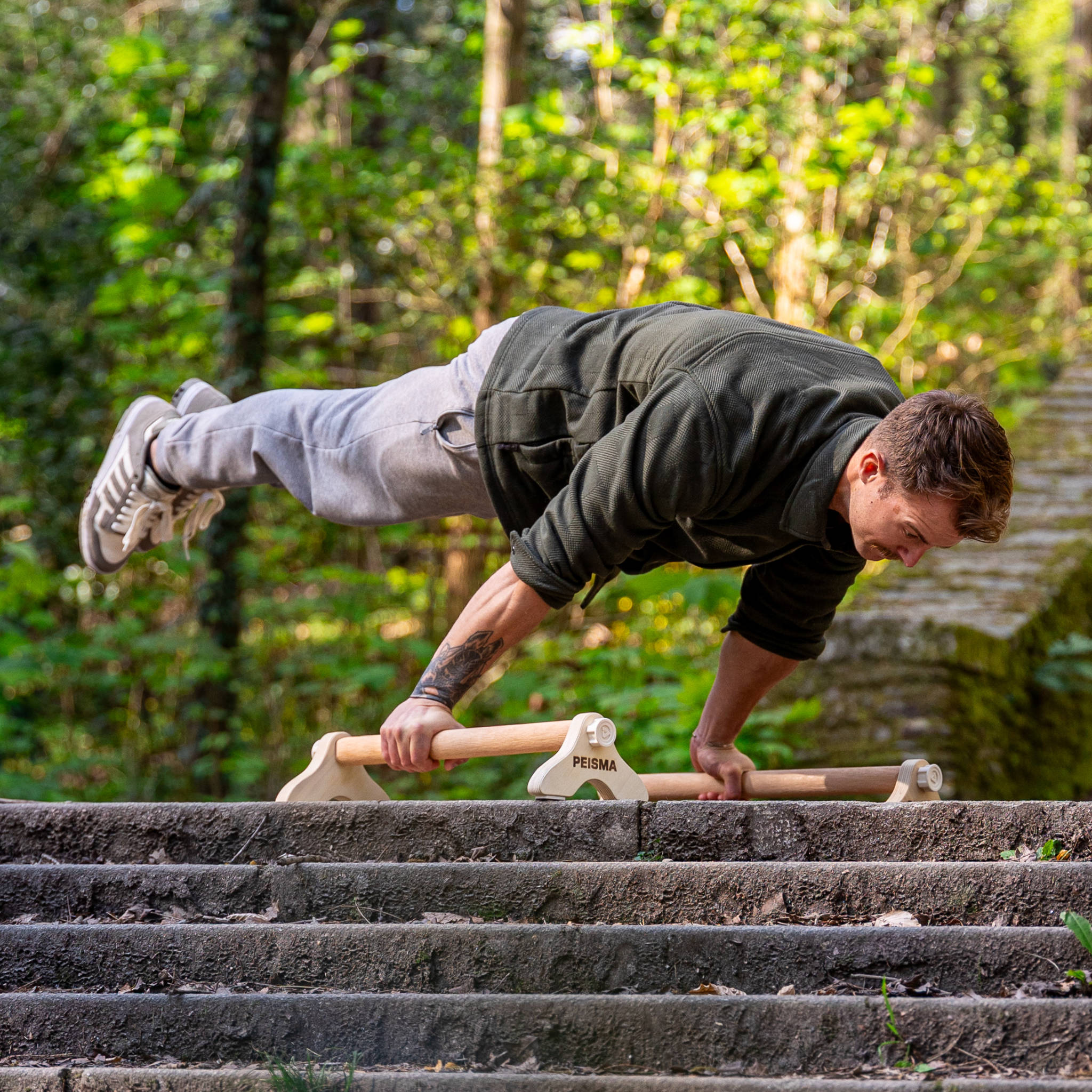 personne faisant une full planche sur des parallettes Peisma en haut d'un escalier dans la nature
